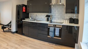 Eine moderne Küche mit dunklen Schränken, einer Edelstahl-Dunstabzugshaube und einem eingebauten Backofen.