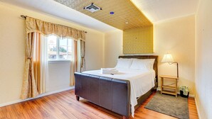 Een hotelkamer met een bed, nachtkastje, lamp en een raam met gordijnen.