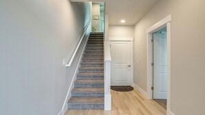 Una escalera con interior alfombrado, una puerta blanca al final y un suelo de madera claro.