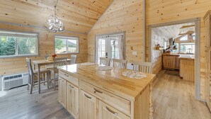 A wooden cabin interior with a dining area, kitchen, and large windows. - Mountain Views: Cabin in Fort Garland Near Hiking (Fort Garland)