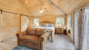 A cozy wooden cabin bedroom with a bed, a chair, a nightstand, and a ceiling fan. - Mountain Views: Cabin in Fort Garland Near Hiking (Fort Garland)