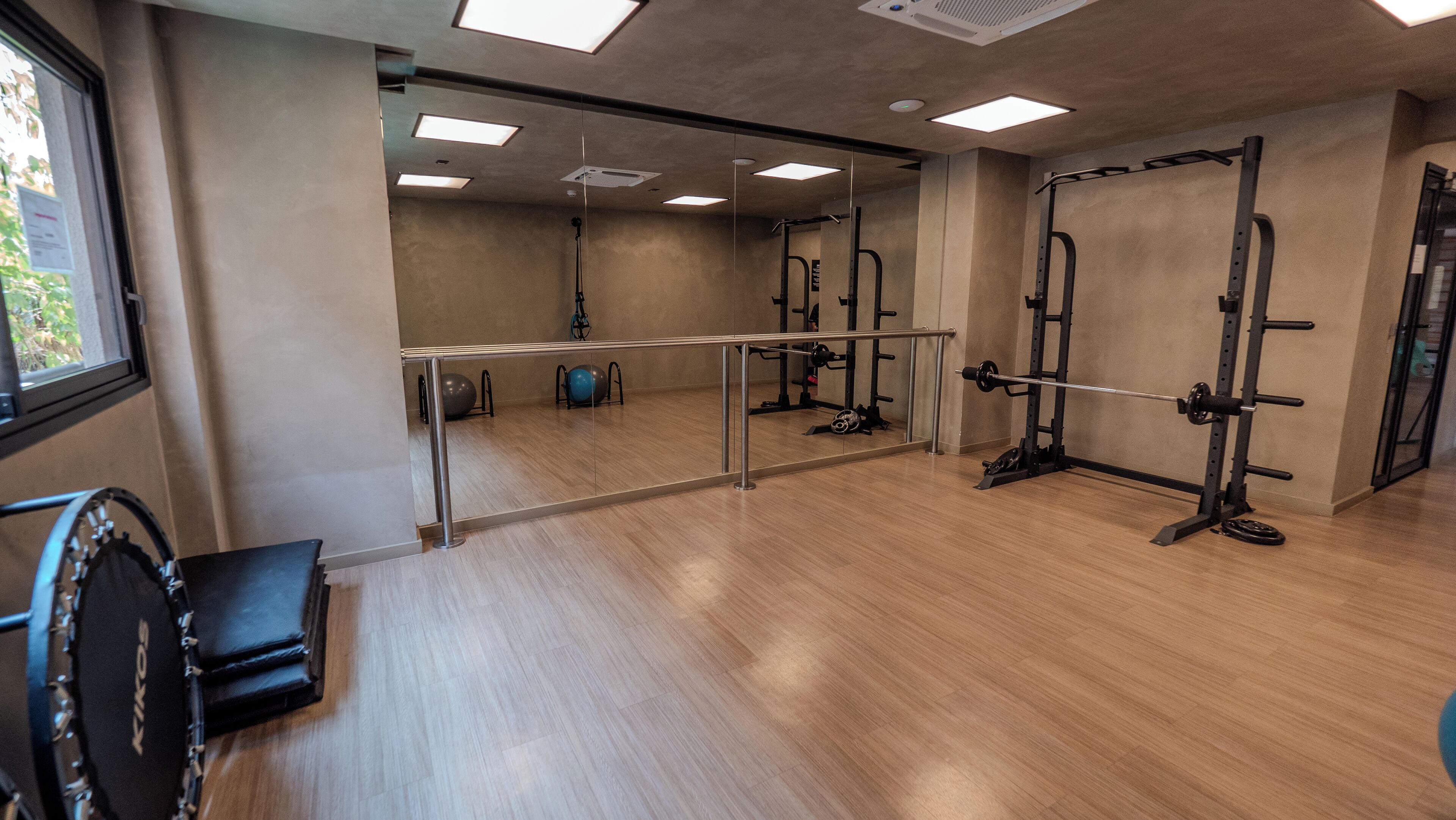 Ett gym med trägolv, träningsutrustning och en vägg täckt med speglar.