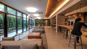 A modern interior with a bar area, seating, and large windows overlooking greenery.