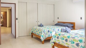 Une chambre avec deux lits, une tête de lit en bois et une armoire.