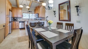 A kitchen with wooden cabinets, a dining table with chairs, a chandelier, and a mirror on the wall. - Walk to Ski Lift: Mtn-View Condo in Mammoth Lakes (Mammoth Lakes)