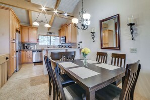 Una cocina con armarios de madera, una mesa de comedor con sillas, una araña y un espejo en la pared.