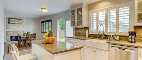 A modern kitchen with white cabinetry, granite countertops, and a central island.