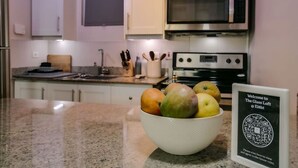 Eine Küche mit einer Obstschale auf der Arbeitsfläche, einer Mikrowelle und einem Backofen. Auf der Arbeitsfläche befindet sich ein Schild mit einem QR-Code.