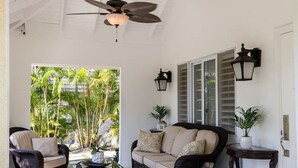 A covered outdoor seating area with wicker furniture, a ceiling fan, and a view of lush greenery. - CTBH @ The Palms at Richmond Estates - Villa #170 [3-Bedroom w/ Pool] (Richmond Estates)