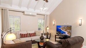 A living room with a sofa, armchairs, a coffee table, a TV, and a ceiling fan. - CTBH @ The Palms at Richmond Estates - Villa #170 [3-Bedroom w/ Pool] (Richmond Estates)