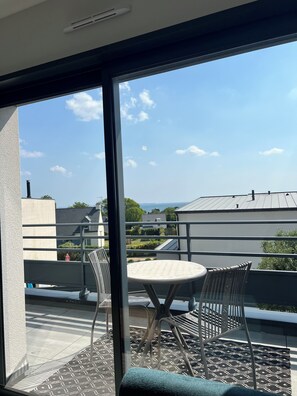 Un balcon avec une table et des chaises, une vue sur le ciel et des bâtiments à l’horizon.