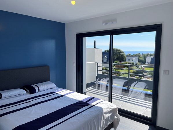 Un dormitorio con una cama grande, vistas al exterior y un balcón.