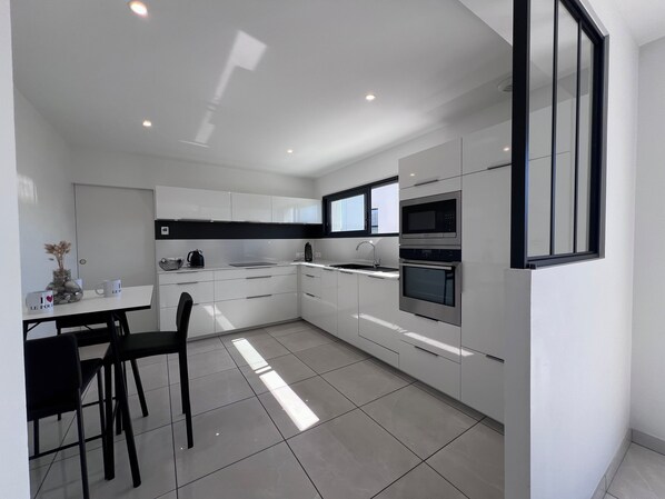 Una cocina moderna con armarios blancos, encimera negra y electrodomésticos de acero inoxidable.