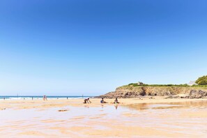 Una playa con gente jugando y relajándose.