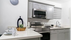 A modern kitchen with stainless steel appliances, a microwave, oven, and a sink.