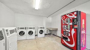 Una sala de lavandería con varias lavadoras y una máquina expendedora de Coca-Cola.