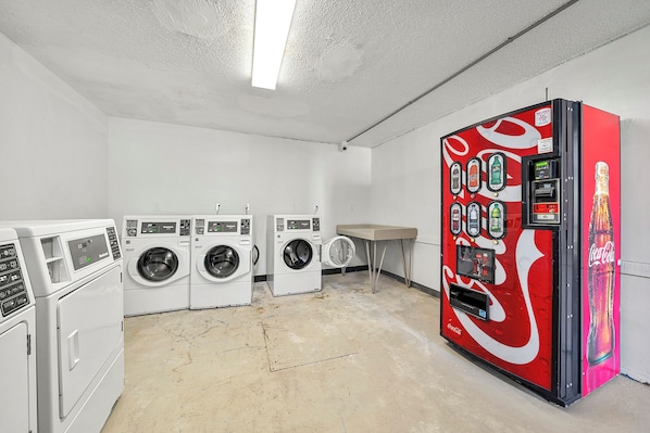 A laundry room with multiple washing machines and a Coca-Cola vending machine.