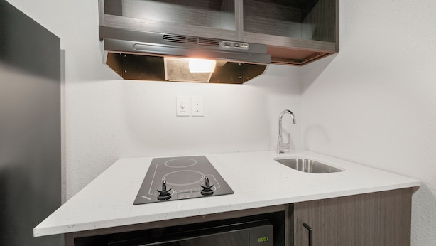 Una cocina compacta con estufa integrada, un lavamanos y un microondas.