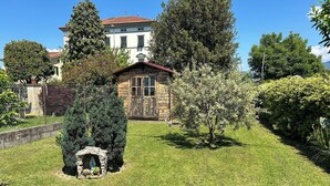 A well-maintained garden with a stone structure, a wooden building, and a large tree.
