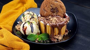 Un plato de postre con una galleta, helado y un postre bañado en chocolate.