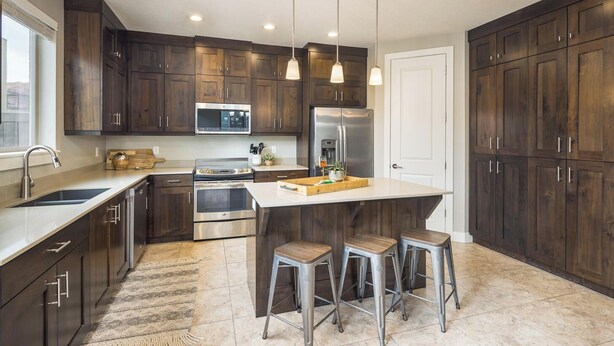 Une cuisine moderne avec des meubles en bois foncé, des appareils électroménagers en acier inoxydable et un îlot central doté de tabourets.