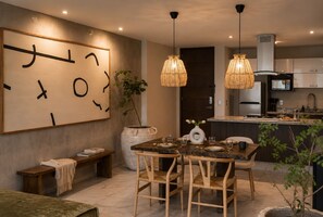 Una cucina moderna con zona pranzo, un'opera d'arte astratta a parete e una pianta in vaso.