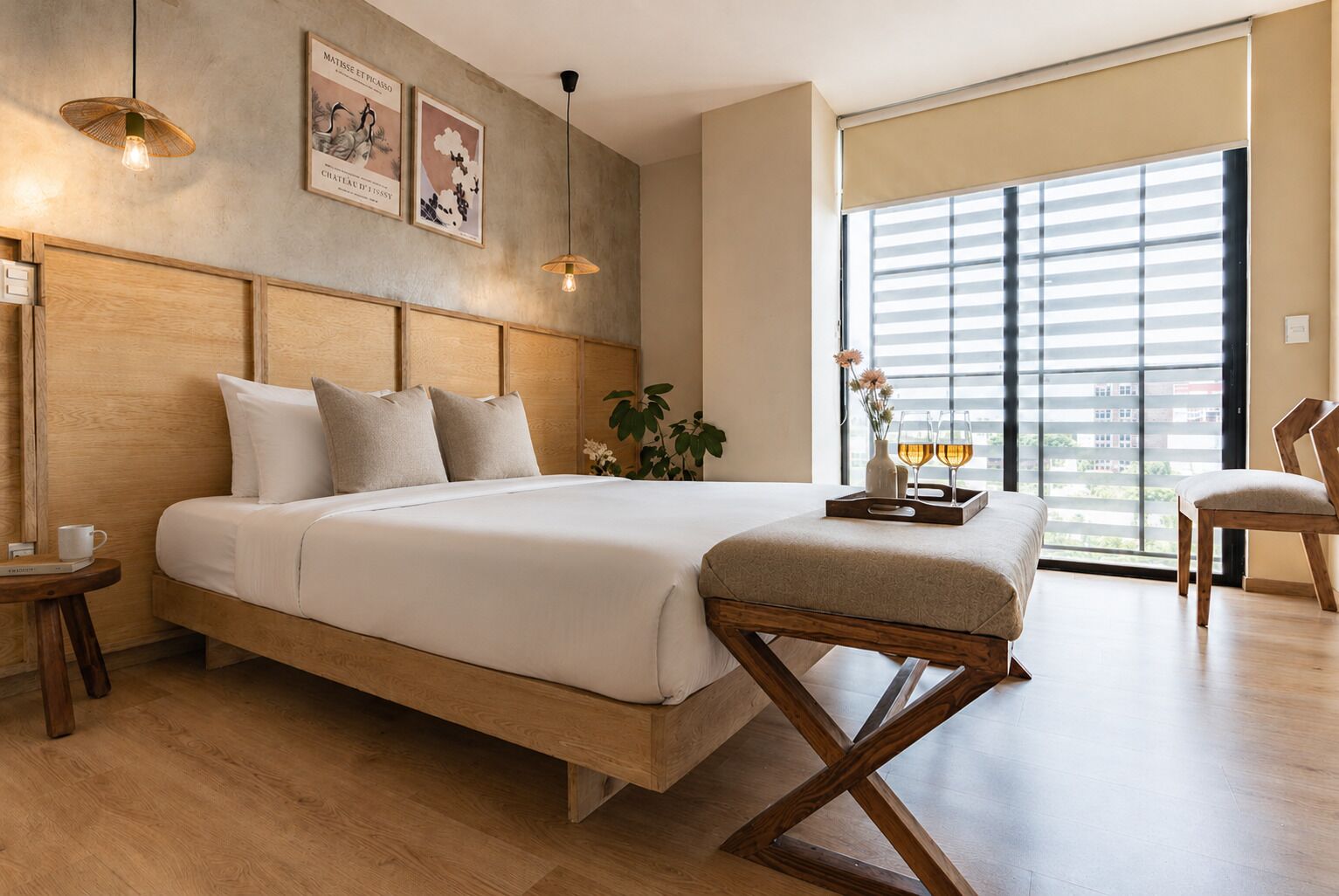 Une chambre moderne avec un lit en bois, une table de chevet, une chaise, une fenêtre avec des stores et des œuvres d’art murales.