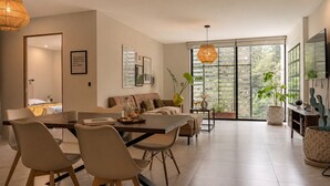 A modern living room with a dining area, large windows, and a view of greenery. - Urban Stylish 3 BedRoom / Daily cleaning (Guadalajara)