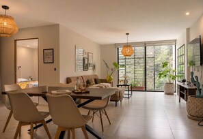 Un salon moderne avec un coin repas, de grandes fenêtres et une vue sur la verdure.