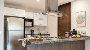 A modern kitchen with a stainless steel refrigerator, granite countertop, and a wooden door. - Urban minimalist 3 BedRoom / Daily Cleaning (Guadalajara)