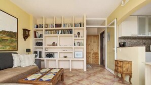 A cozy living room with a sofa, a coffee table, and a bookshelf filled with books and decorative items.