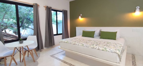 A bedroom with a bed, a small table, chairs, a window with curtains, and a wall-mounted light. - 1 Block to Beach, Garden, Air, Kitchenette, C4 (Holbox)