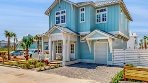 A two-story house with a garage, a covered porch, and a paved driveway. - Gorgeous family beach home with balcony and wonderful amenities (Port Aransas)