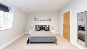 A bedroom with a bed, two bedside tables, a window, a door, and a mirror. - Stunning Central Windsor Town House (Windsor)