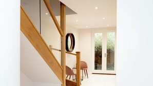 A modern interior with a wooden staircase, a round mirror, and a seating area with two chairs. - Stunning Central Windsor Town House (Windsor)