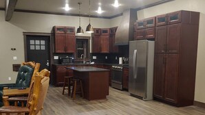 A spacious kitchen with wooden cabinets, a central island, and a refrigerator. - The Bunkhouse, charming 2-bedroom farmhouse (Priest River)