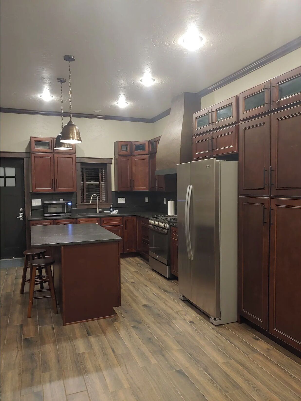 A kitchen with wooden cabinets, a stainless steel refrigerator, a microwave, and a gas stove.