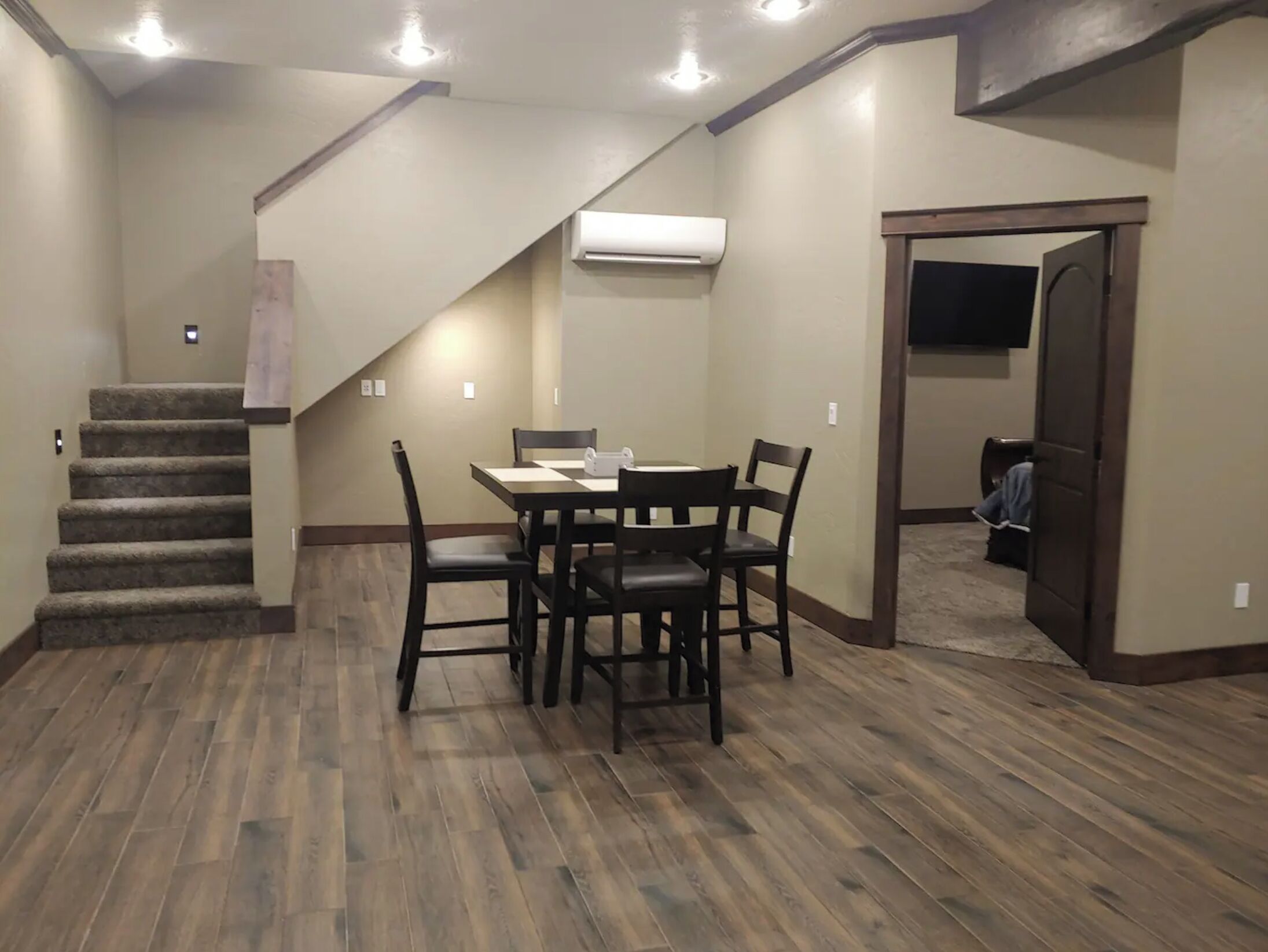 A dining area with a table and chairs, a staircase, and an air conditioning unit.