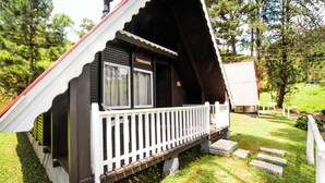 A chalet-style building with a white porch and a chimney. - Hotel Fazenda Floresta Negra (Camanducaia)