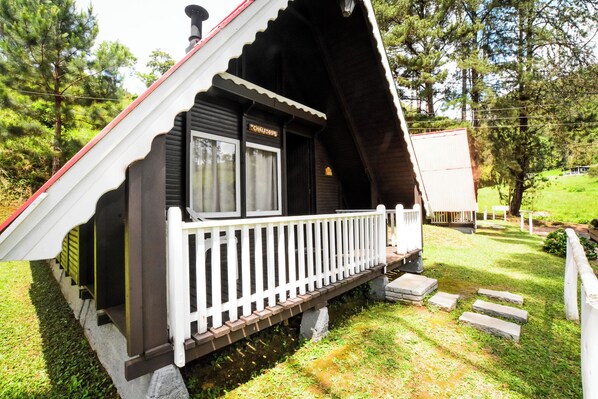 A chalet-style building with a white porch and a chimney. - Hotel Fazenda Floresta Negra (Camanducaia)
