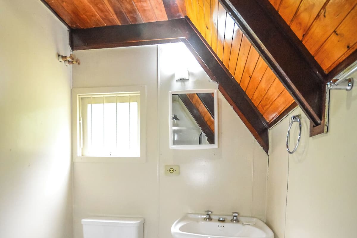 Un baño pequeño y sencillo con inodoro, lavamanos y espejo.