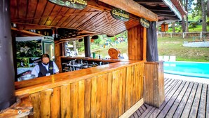 A wooden bar area with signs reading "Coquetel de Frutas" and "Calpinha". - Hotel Fazenda Floresta Negra (Camanducaia)