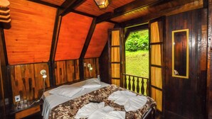 A wooden room with a bed, a window, and a view of greenery outside. - Hotel Fazenda Floresta Negra (Camanducaia)