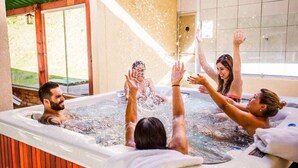 A hot tub with people enjoying the water, surrounded by a tiled wall and a window. - Hotel Fazenda Floresta Negra (Camanducaia)