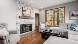 A living room with a fireplace, a large window, and a cozy seating area.