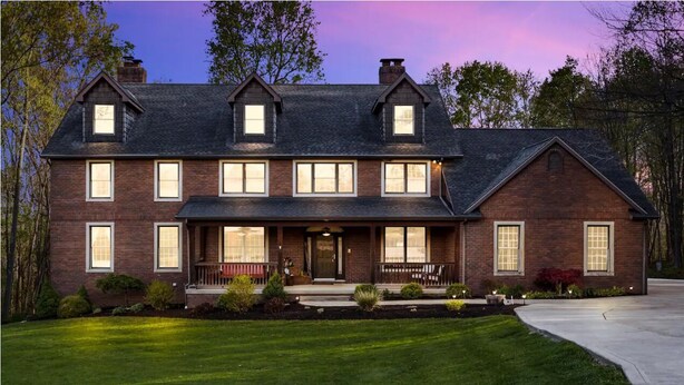 A large, two-story brick house with a symmetrical facade, multiple windows, and a well-maintained front yard.