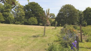 A grassy field with trees and wildflowers. - ESCALE DE GERBOLD (Gratot)