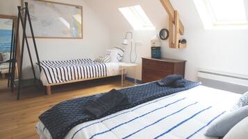 A bedroom with two beds, a wooden dresser, a map on the wall, and skylights.