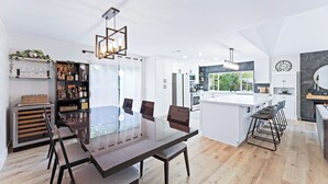 A modern kitchen with white cabinets, a central island, and bar stools.