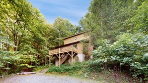 Eine Holzhütte mit einer Terrasse, umgeben von dichtem Wald.